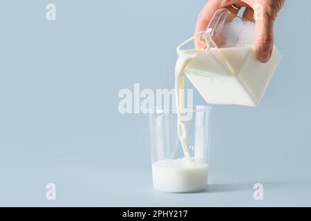 Versare latte organico in vetro su sfondo blu. Spazio di copia. Giornata mondiale del latte. Foto Stock