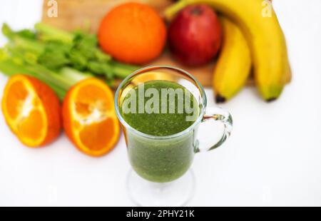 frullato sano in vetro e frutta tutto intorno su tavola di legno Foto Stock