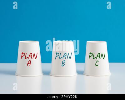 Per trovare e scegliere il piano migliore e appropriato. Opzioni e alternative di business plan. Tre tazze di carta con le parole piano a, piano b e piano c on Foto Stock