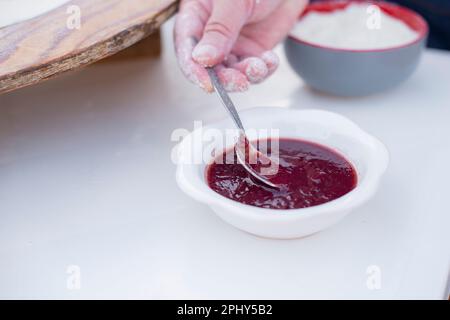 Vecchia cuoca femminile, chef che prepara pita, prendere salsa, ketchup con cucchiaio, cucinare all'aperto. Foto Stock