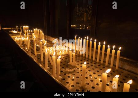 Una grande quantità di candele accese all'interno di una chiesa Foto Stock