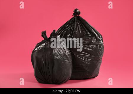 Sacchi di rifiuti pieni di rifiuti su sfondo rosa Foto Stock