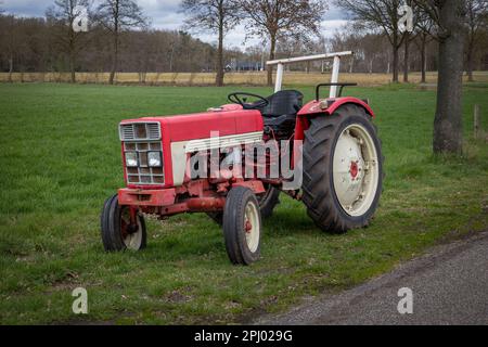 Vecchio trattore rosso d'annata sul lato della strada, precedentemente utilizzato dagli agricoltori per lavorare il terreno, provincia di Overijssel, Paesi Bassi Foto Stock