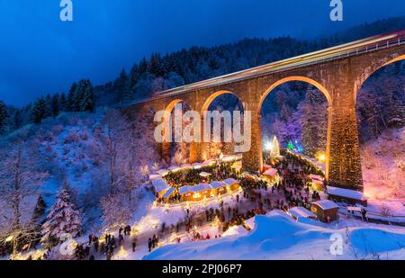 Mercatino di Natale nella Gola di Ravenna nella Foresta Nera innevata, il viadotto ferroviario della Hoellentalbahn è illuminato con colori vivaci, Foresta Nera Foto Stock