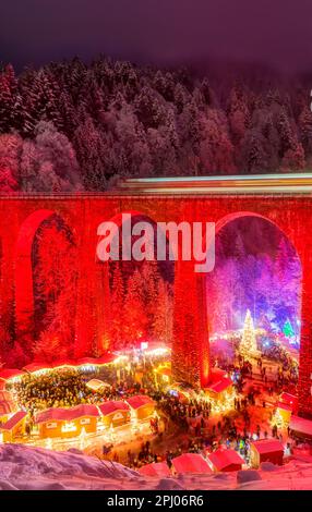 Mercatino di Natale nella Gola di Ravenna nella Foresta Nera innevata, il viadotto ferroviario della Hoellentalbahn è illuminato con colori vivaci, Foresta Nera Foto Stock