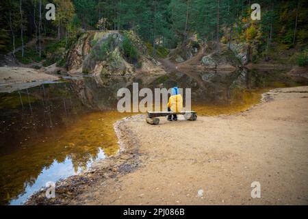 Il bambino sta riposando su una panchina al bordo del lago nel mezzo della foresta. Montagne polacche Foto Stock