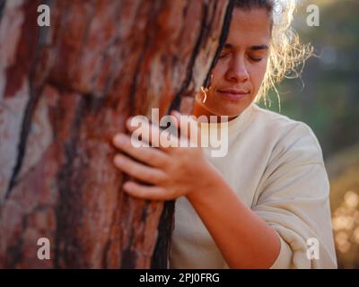 la donna ama la natura che abbraccia il pino, nessun concetto di deforestazione e celebrazione del giorno della terra, cura per la terra, meditazione, salvare il nostro pianeta per bello e essere Foto Stock