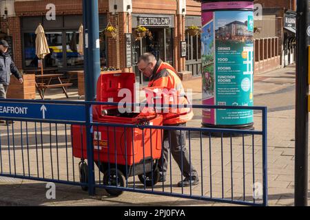 Postman posto di smistamento dal suo carrello a quattro ruote in Great Yarmouth Norfolk Inghilterra UK Foto Stock