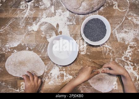 Impastare a mano l'impasto. Persone che fanno l'impasto per il pane durante il laboratorio di preparazione del pane. Farina e pasta cruda su tavolo di legno Foto Stock