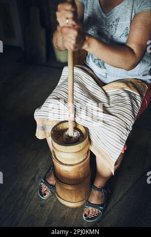 Donna che fa burro con burro churn. Vecchio metodo tradizionale di fabbricazione del burro Foto Stock