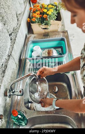 Donna che lava i piatti pentole e piatti nella cucina all'aperto durante le vacanze in campeggio. Vita in campo Foto Stock