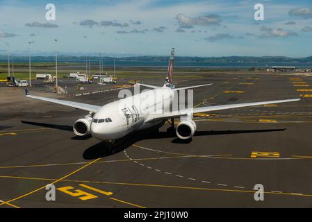 Fiji Airways Airbus A330 Airliner jet plane DQ-FJV tassando allo stand presso l'aeroporto di Auckland, Nuova Zelanda. Marcature per il cancello. Manukau Harbour oltre Foto Stock