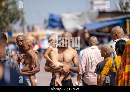 Haridwar, Uttarakhand, India - Ottobre 2022: Ritratto di un maschio non identificato che porta il suo bambino in armi dopo aver radito la testa a s parte del rituale. Foto Stock