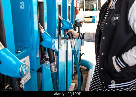 Hockenheim, Germania - 29 marzo 2023: Giovane donna che rifornisce l'auto alla stazione di servizio self-service, ugelli di rifornimento della pompa di benzina Foto Stock