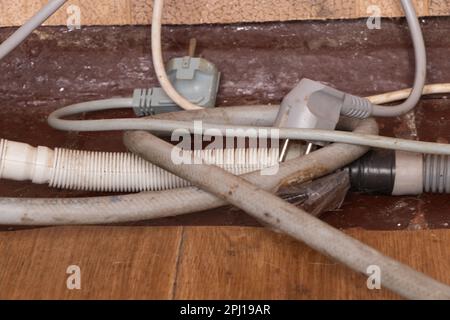 i fili elettrici e i tubi flessibili di scarico si trovano sul vecchio pavimento sporco Foto Stock