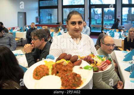 Berlino, Germania. 30th Mar, 2023. Una donna serve cibo presso la Casa del suo multifaith veloce-breaking evento presso il campus Wilhelmstadtschulen a Spandau. Il mese del digiuno del Ramadan è di particolare importanza per i musulmani. Durante il giorno, non si mangia alcun cibo e poi la sera, la rottura del digiuno è spesso celebrata insieme. Credit: Paul Zinken/dpa/Alamy Live News Foto Stock