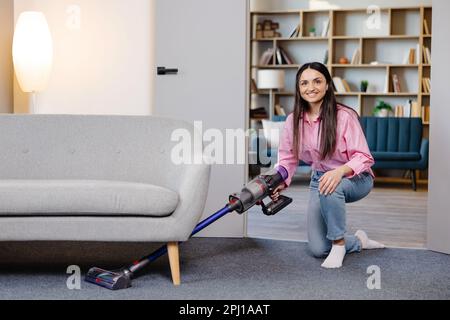 Felice giovane governante tappeto pulizia con aspirapolvere in camera di  albergo Foto stock - Alamy