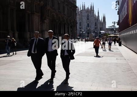 Uomini che camminano di fronte al Duomo di Milano nel centro di Milano Foto Stock
