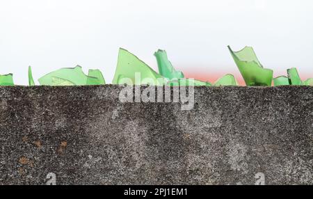 Pezzi di vetro rotto sulla cima di un muro di cemento Foto Stock