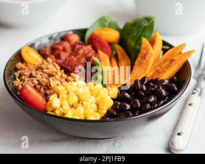 Insalata di patate dolci con spinaci, TVP, mais, fagioli neri, salsa di pomodoro e pomodori ciliegini Foto Stock