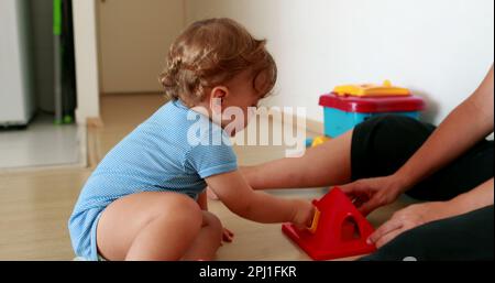 Il bambino che ha successo stringe le mani. Un bambino bambino di un anno risolvere puzzle Foto Stock