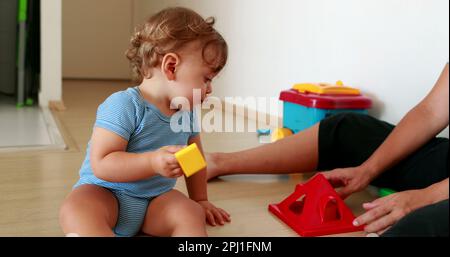 Il bambino che ha successo stringe le mani. Un bambino bambino di un anno risolvere puzzle Foto Stock