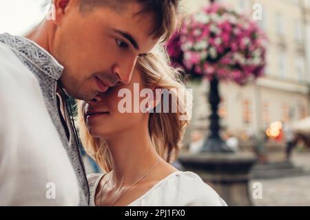 Primo piano ritratto di coppia amorevole a piedi nella vecchia città di Lviv indossando tradizionali camicie nazionali ucraine. Uomo e donna abbracciano all'aperto. Spazio Foto Stock