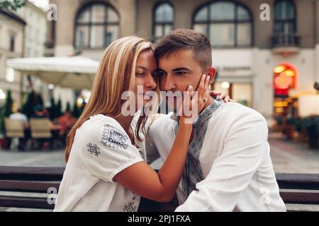 Coppia amorevole rilassarsi nella vecchia città di Lviv indossando le camicie nazionali tradizionali ucraine. Gli sposi novelli trascorrono del tempo insieme sulla piazza Foto Stock