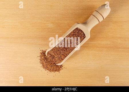 Rooibos tè medio tagliato in legno scoop su tavola di legno. Rooibos in latino Aspalathus linearis. erba. tè alle erbe. ingrediente alimentare. vista dall'alto. Foto Stock