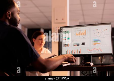 Project manager che analizza i risultati della ricerca aziendale su schermo del computer, report aziendale analisi dei dati. Dipendenti afro-americani che controllano le statistiche in uno spazio di coworking con luce al tramonto Foto Stock