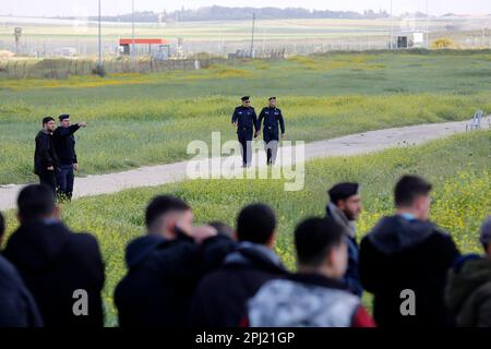 I poliziotti palestinesi oltrepassano la recinzione tra Israele e la striscia di Gaza mentre i palestinesi prendono parte a una protesta che segna la "Giornata della terra" lungo il confine tra Israele e la striscia di Gaza, nella striscia di Gaza orientale. La 'Giornata della terra' commemora gli eventi del 30 marzo 1976, quando nelle città arabe sono state organizzate marce e uno sciopero generale contro la decisione del governo israeliano di espropriare grandi tratti di terra di proprietà palestinese per l'insediamento. L'evento annuale chiede ai palestinesi il diritto di ritornare nella terra da cui sono stati sfollati dopo la creazione di Israele nel 1948. Foto Stock