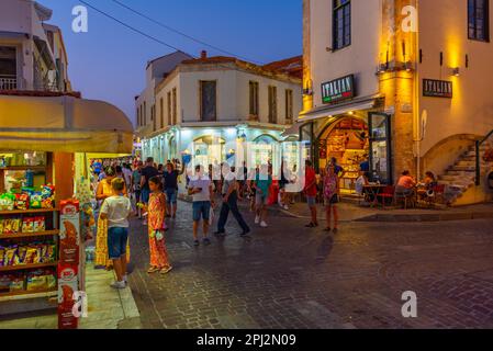 Rethimno, Grecia, 20 agosto 2022: Tramonto vista di persone che passeggiando in una strada turistica nella città greca Rethimno a Creta isola. Foto Stock