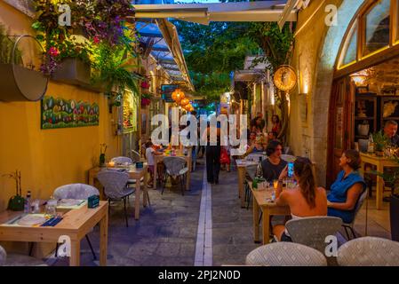 Rethimno, Grecia, 20 agosto 2022: Tramonto vista di persone che passeggiando in una strada turistica nella città greca Rethimno a Creta isola. Foto Stock