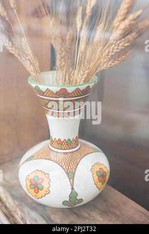 Spighe secche di grano in vaso vintage su fondo in legno. Autunno, autunno, giorno di ringraziamento concetto. Copia spazio Spikelets di grano in vaso di ceramica Foto Stock