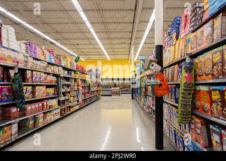 Una donna lontano acquirente visto in produzione alla fine della corsia di cereali in scatola in un Walmart Supercenter a Wichita, Kansas, USA. Foto Stock