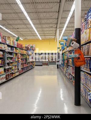 Una donna lontano acquirente visto lungo la corsia di cereali in scatola nel reparto di produzione in un Walmart Supercenter a Wichita, Kansas, USA. Foto Stock