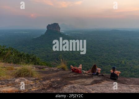 Sigiriya, Sri Lanka, 4 febbraio 2022: Gruppo di giovani gode di una vista al tramonto della fortezza rocciosa di Sigiriya in Sri Lanka. Foto Stock