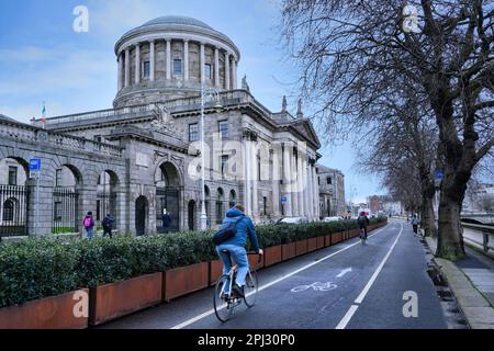 Dublino ha un sacco di ciclisti, che fanno uso di una grande rete di piste ciclabili, come questa accanto al fiume Liffey, di fronte ai quattro campi Foto Stock