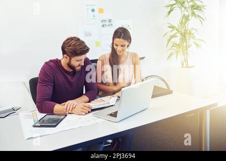 Due teste sono meglio di una. due giovani architetti che lavorano su un computer portatile. Foto Stock