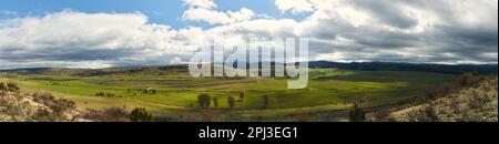 Una vista panoramica di un vasto campo verde con splendide nuvole che gettano ombre su Galve de Sorbe, nella regione spagnola della Sierra Norte de Guadalajara. Foto Stock