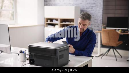 Uomo d'affari che dà il comando di stampa sullo smartphone in ufficio Foto Stock