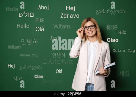 Ritratto di traduttore felice e parole di saluto in diverse lingue straniere su sfondo verde Foto Stock