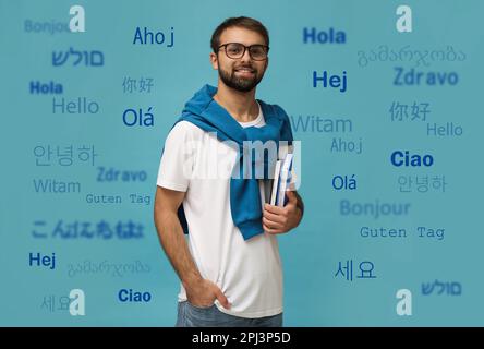 Ritratto di traduttore felice e parole di saluto in diverse lingue straniere su sfondo azzurro Foto Stock