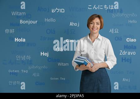 Ritratto di traduttore felice e parole di saluto in diverse lingue straniere su sfondo azzurro Foto Stock