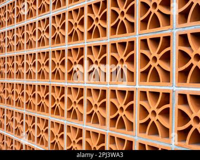 edificio in terracotta con ventilazione ad aria. Blocco di ventilazione con motivo floreale moderno su grande sfondo parete. Foto Stock