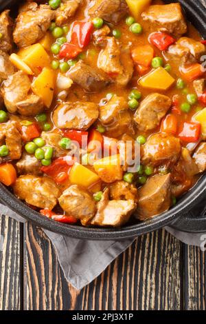 Delizioso piatto di manzo con verdure in un primo piano di succo in una pentola su un tavolo di legno. Vista verticale dall'alto Foto Stock