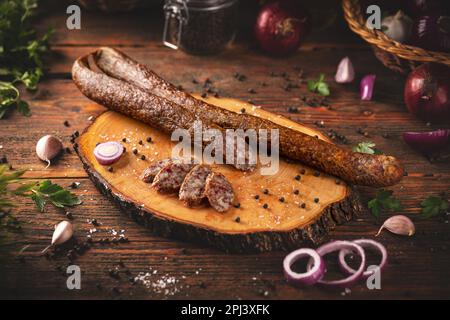 Salsiccia affumicata su un tavolo rustico in legno con spezie Foto Stock