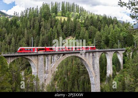 Davos Wiesen - Giugno 24. 2021: Un treno passeggeri rosso attraversa il famoso viadotto Wiesener sulla linea ferroviaria Davos - Filisur, è il viadu più alto Foto Stock