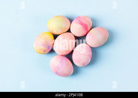 Uova di Pasqua dipinte in giallo rosa e verde su sfondo blu con un posto per il testo. Buon concetto di Pasqua. Biglietto d'auguri. Foto Stock