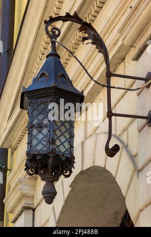 Applique da strada in vecchio stile in metallo nero. Facciata grigia di una vecchia casa. Lviv, Ucraina. Foto Stock